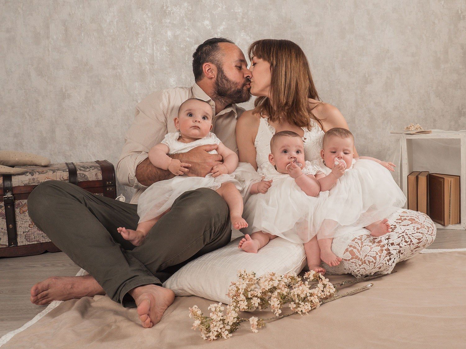 Una pareja se besa con sus bebés en brazos